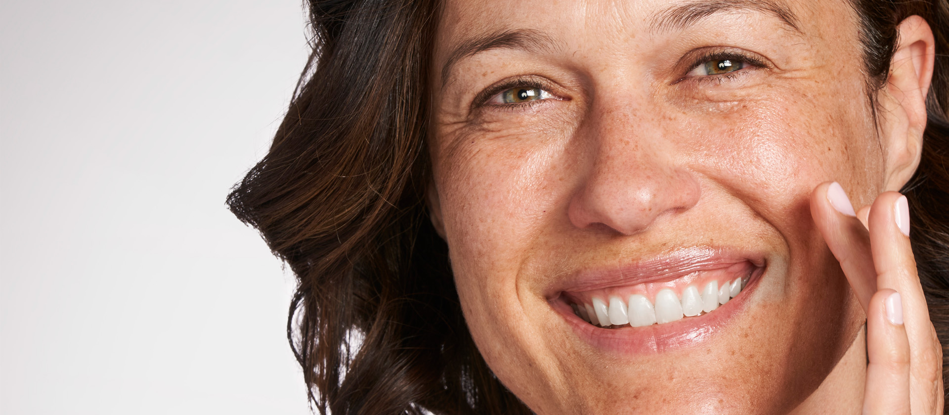 Bild som visar glad kvinna som applicerar hudvård.