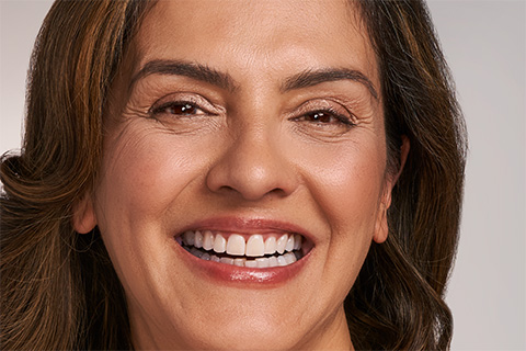 Bild på leende kvinna som tar hand om sitt dekolletage med en halskräm.