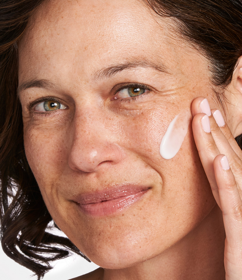 Kvinna som applicerar hudkräm på sin kind.