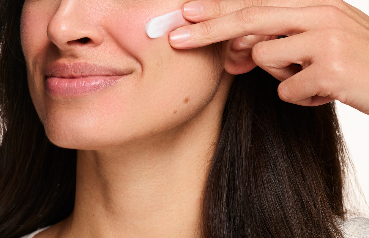 Bild på kvinna som applicerar en hudkräm som stärker hudens barriär.